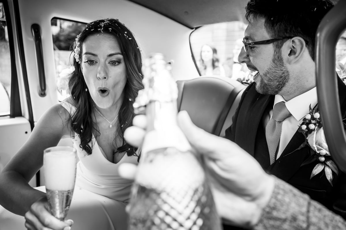 The bride pulls a funny face as her champagne glass bubbles over