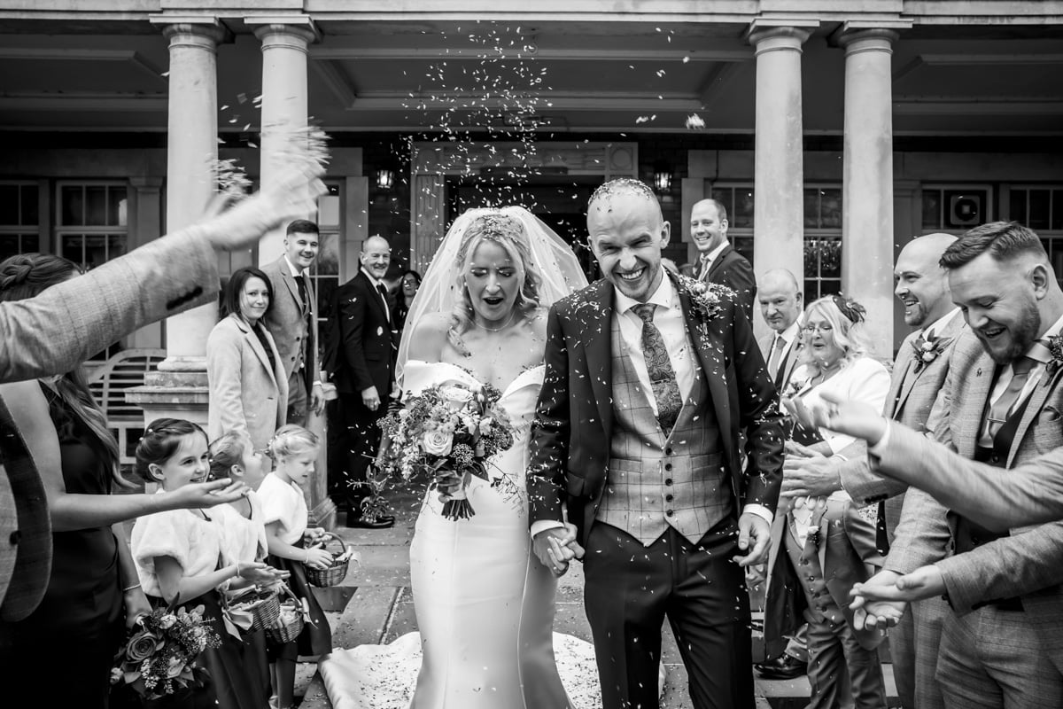 Guests shower the bride and groom with confetti at Eaves Hall