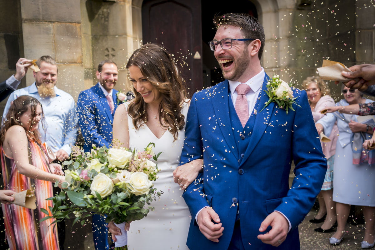 The bride and groom are showered with confetti outside St Mary’s RC Church
