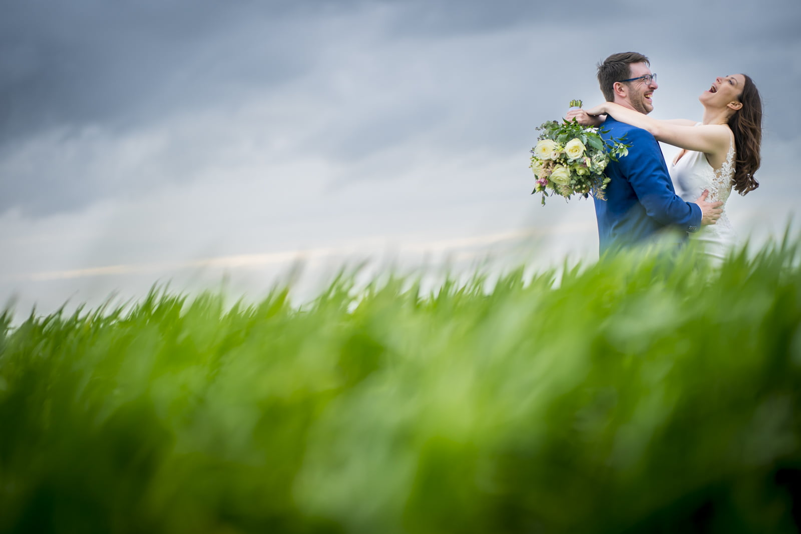 The bride and groom embrace in a field in the middle of nowhere
