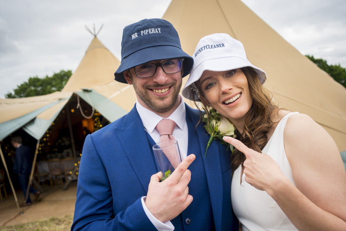The bride and groom wear silly hats tipi wedding photography