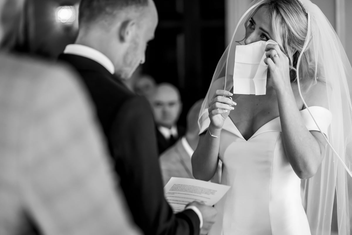 The bride wipes away a tear as the groom reads his vows