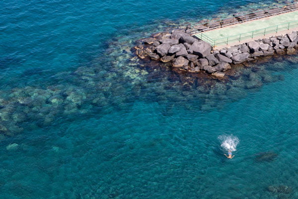 A man swims in the sea at a destination wedding in Italy