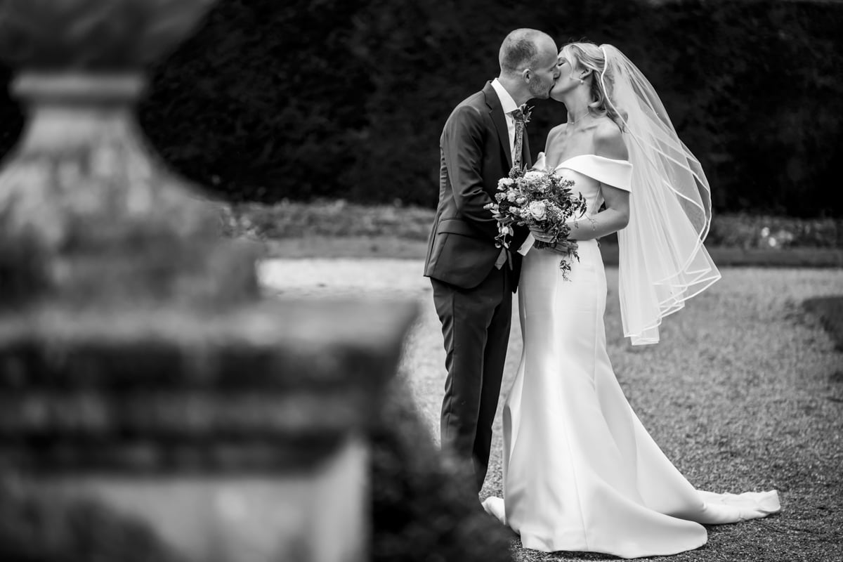 The bride and groom kiss in the grounds of Eaves Hall