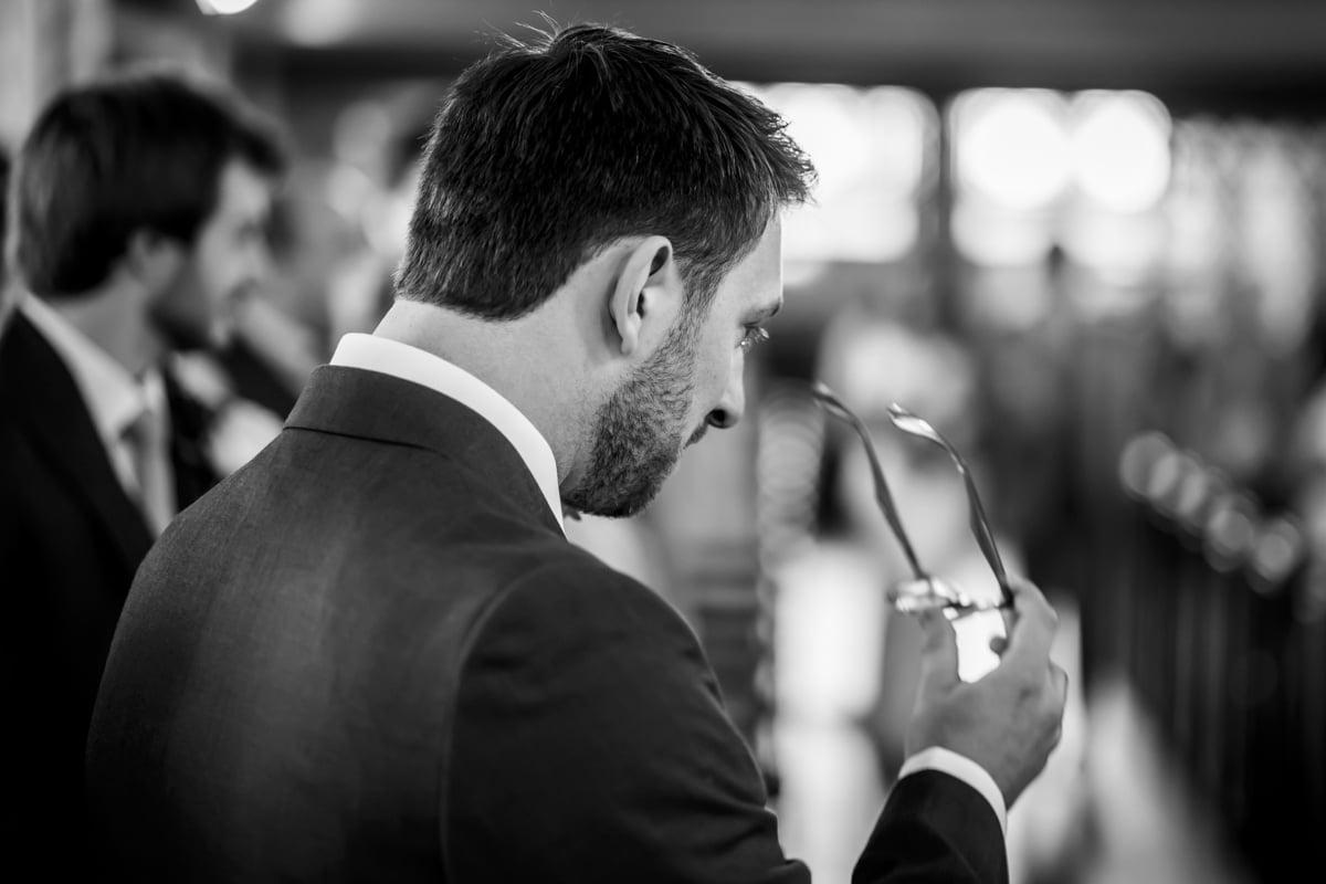 The groom takes of his glasses in anticipation of the bride walking down the aisle