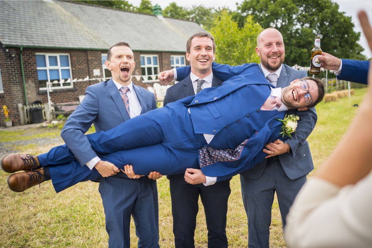 The groom is held up by his groomsmen