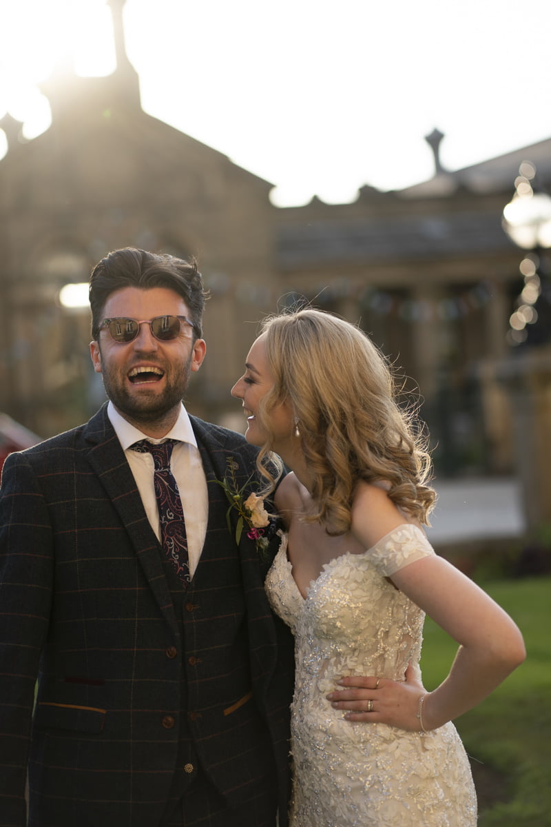 The bride laughs at the groom in his sunglasses