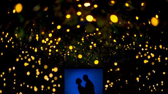 The bride and groom are silhouetted against the scattered lighting creative wedding photography